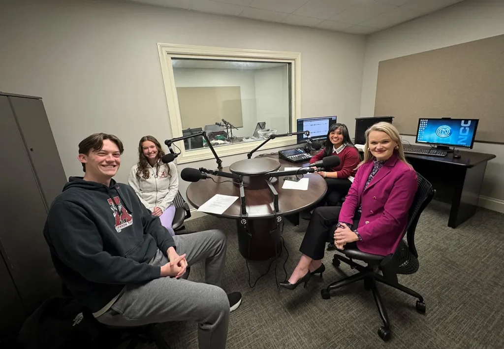 Fit2BTide radio show hosts and guests gathered around microphones